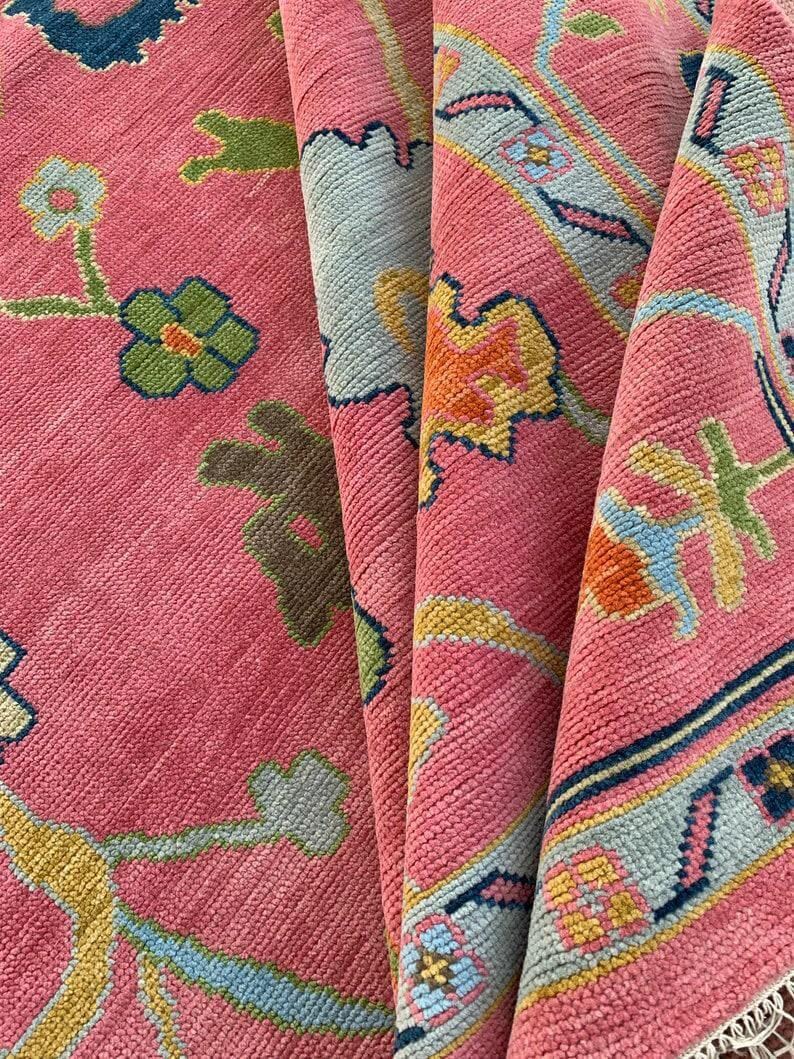 Vibrant pink area rug with colorful floral motifs and geometric border.