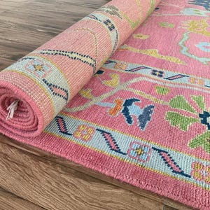 Traditional oriental pink rug with oversized flowers and vine patterns.