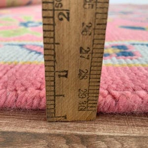 Hand-knotted pink rug with oriental design for bedroom or living space.
