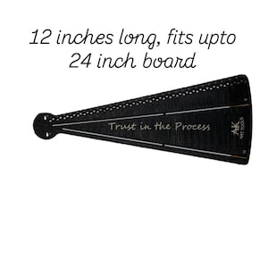 Peut inclure: Règle AK Large noire, de 30,48 cm de long, conçue pour s'adapter à une planche de 60,96 cm. La règle a une forme triangulaire avec une extrémité circulaire et porte l'inscription "Trust in the Process".