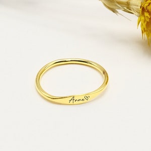 May include: A gold ring engraved with the name "Anne" and a small heart.