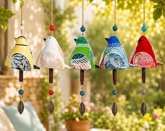 May include: Five hanging bird-shaped wind chimes in yellow, white, green, blue, and red. Each ceramic bird features intricate white floral patterns on the wings, a wooden clapper, colorful beads on the twine, and a metallic leaf-shaped pendant.