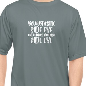 May include: A gray short-sleeved t-shirt with white text that reads "Bombastic Side Eye Criminal Offense Side Eye".