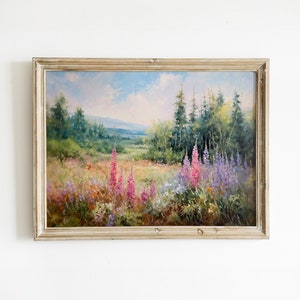 May include: A framed oil painting depicting a landscape scene with a forest in the background and a field of wildflowers in the foreground. The painting features a variety of colors, including green, blue, and pink.