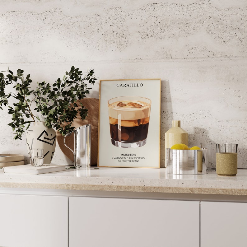 May include: A framed poster with a graphic illustration of a cocktail called "Carajillo". The poster has a white background with black text and a brown wooden frame. The cocktail is in a glass with ice and coffee beans. The poster is on a countertop with a vase of greenery, a pitcher, and a bowl of lemons.