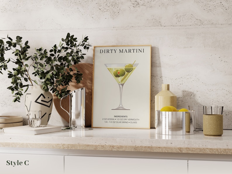 Puede incluir: Un p&oacute;ster enmarcado con el texto "Dirty Martini" y una ilustraci&oacute;n de una copa de martini con aceitunas. Los ingredientes para un dirty martini se enumeran debajo de la ilustraci&oacute;n: 2 oz de vodka, 1/2 oz de vermut seco, 5 1/2 oz de salmuera de aceitunas y aceitunas.