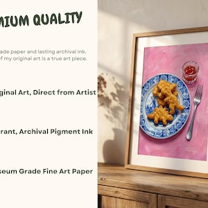 K&ouml;nnte beinhalten: Ein gerahmter Druck mit einem Stillleben von Dinosaurier-Nuggets auf einem blau-wei&szlig;en Teller, mit einem kleinen Glas Ketchup und einer Gabel. Der Hintergrund ist einfarbig rosa. Der Druck ist mit "Premium Quality" beschriftet.