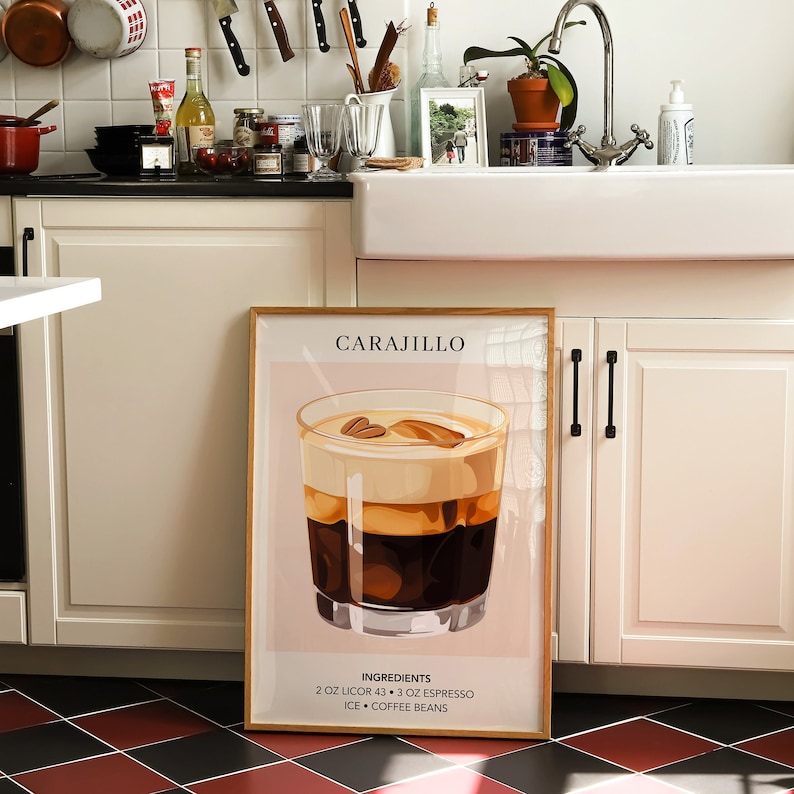 May include: A framed print with a light pink background featuring a glass of Carajillo, a cocktail made with coffee and liquor. The text "Carajillo" is at the top of the print, and the ingredients are listed at the bottom: "2 oz Licor 43, 3 oz Espresso, Ice, Coffee Beans".