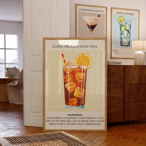May include: A vintage-style poster with a colorful illustration of a Long Island Iced Tea cocktail. The poster has a light beige background with a brown wooden frame. The text on the poster reads "Long Island Iced Tea" and lists the ingredients for the cocktail.