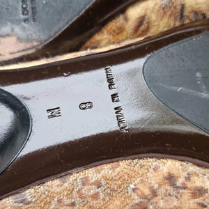 May include: Close-up of the sole of a shoe with a leopard print design. The shoe size is 8 M. The words "MADE IN ITALY" are printed on the sole.
