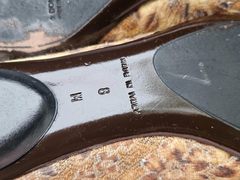 May include: Close-up of the sole of a shoe with a leopard print design. The shoe size is 8 M. The words "MADE IN ITALY" are printed on the sole.