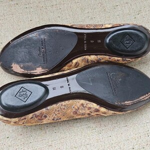 May include: A pair of women's flats with a leopard print design. The soles are dark brown with a black heel pad and the brand name "Donald J Pliner" is visible. The shoes are size 9 M.