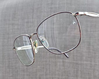 Peut inclure: Une paire de lunettes à monture argentée avec des verres transparents. Les lunettes sont nettes et l'arrière-plan est flou.