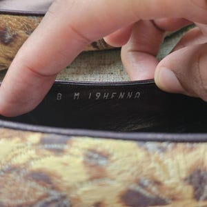 May include: Close-up of a shoe's interior, revealing the size and style details. The shoe features a brown and tan animal print pattern. The size is marked as 8 M.