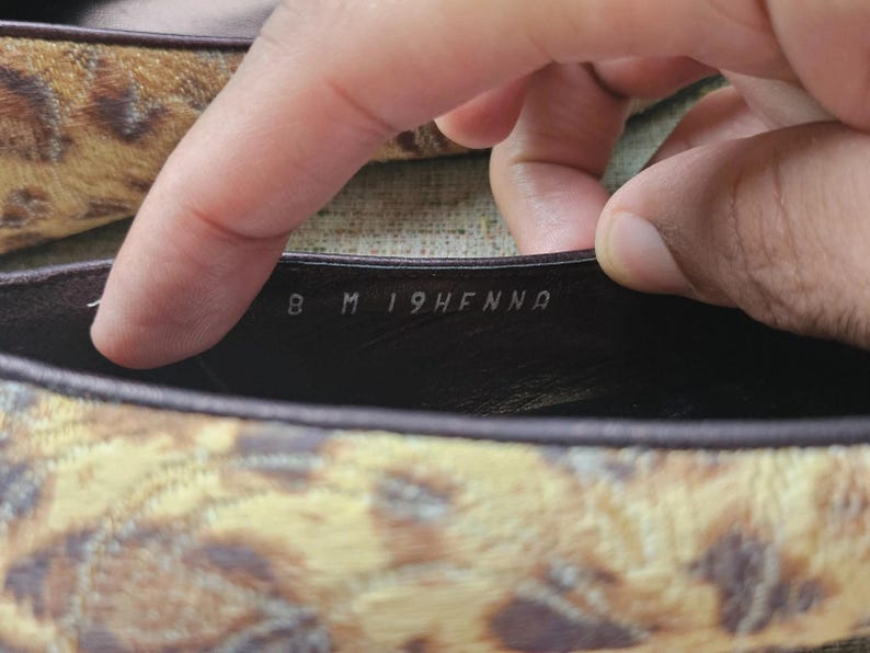 May include: Close-up of a shoe's interior, revealing the size and style details. The shoe features a brown and tan animal print pattern. The size is marked as 8 M.