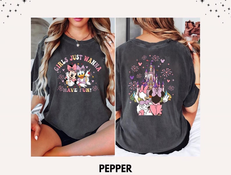May include: Dark grey t-shirt featuring Minnie Mouse and Daisy Duck with the text "GIRLS JUST WANNA HAVE FUN!" on the front. The back of the shirt shows a castle with fireworks and the same characters. The shirt is a comfortable, casual style.