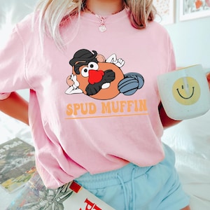 May include: A pink t-shirt with a cartoon image of Mr. Potato Head with the text "Spud Muffin".