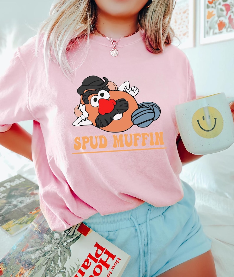 May include: A pink t-shirt with a cartoon image of Mr. Potato Head with the text "Spud Muffin".