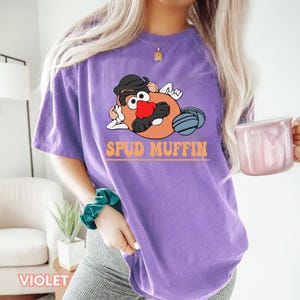 May include: Purple t-shirt with a cartoon image of Mr. Potato Head with the text "Spud Muffin".