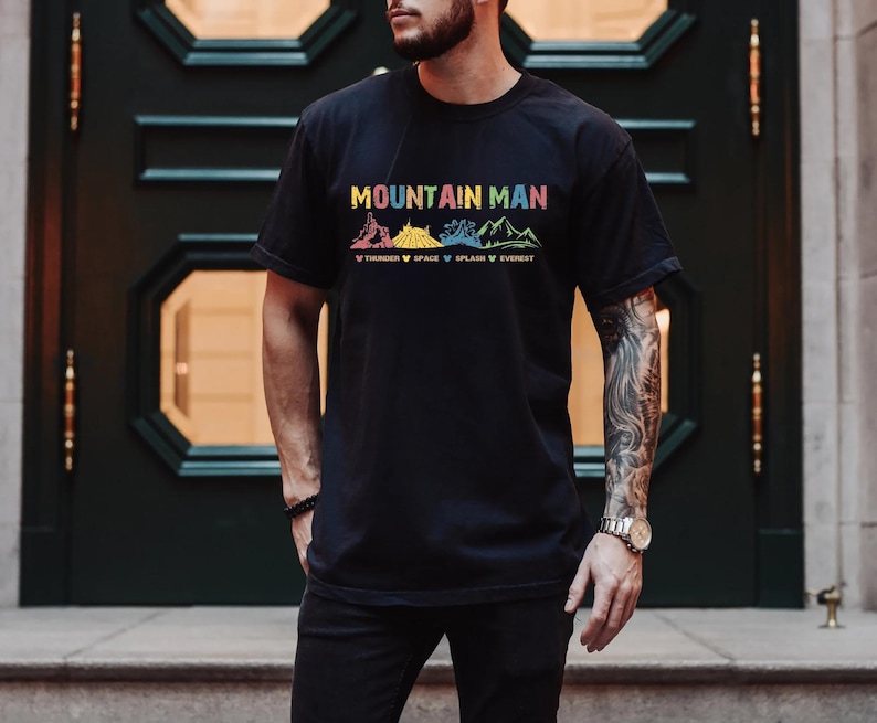 May include: A black t-shirt with the text "Mountain Man" and a graphic of mountains with the words "Timber", "Space", "Splash", and "Everest" underneath.