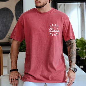 May include: A red t-shirt with a white graphic that says "Cool Dads Club" in a circle.