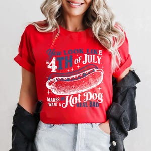 May include: Red t-shirt with a white graphic of a hot dog and the text "You look like the 4th of July. Makes me want a hot dog real bad."