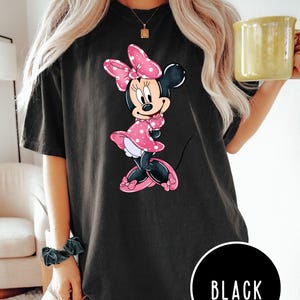 May include: Black oversized t-shirt featuring a cartoon image of Minnie Mouse in a pink polka dot dress with a pink bow. The text "BLACK" is visible in the lower right corner of the image.
