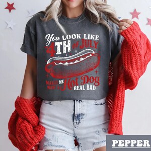 May include: A gray t-shirt with a distressed look featuring a white graphic of a hot dog with the text "You look like the 4th of July, Makes me want a hot dog real bad".