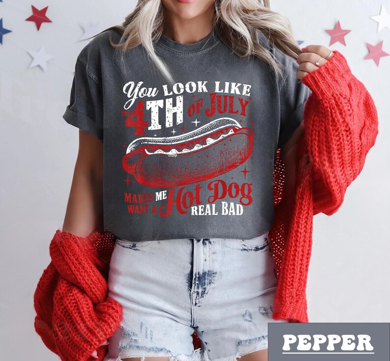 May include: A gray t-shirt with a distressed look featuring a white graphic of a hot dog with the text "You look like the 4th of July, Makes me want a hot dog real bad".