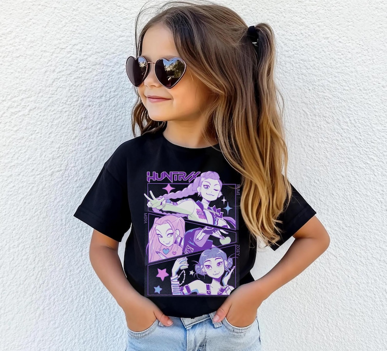 Peut inclure: Un t-shirt noir avec un motif graphique avec le mot "HUNTRA" et trois personnages de style anime en violet et blanc. La fille sur l'image porte des lunettes de soleil en forme de c&oelig;ur et un jean bleu.