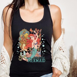May include: Black tank top with a graphic print of Ariel, the Little Mermaid, with Prince Eric and other characters from the Disney movie. The text "The Little Mermaid" is printed below the image.