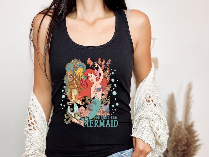 May include: Black tank top with a graphic print of Ariel, the Little Mermaid, with Prince Eric and other characters from the Disney movie. The text "The Little Mermaid" is printed below the image.