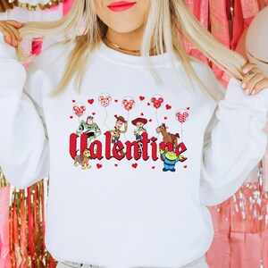 May include: White sweatshirt with a red "Valentine" graphic featuring characters from the Toy Story franchise holding red heart balloons.