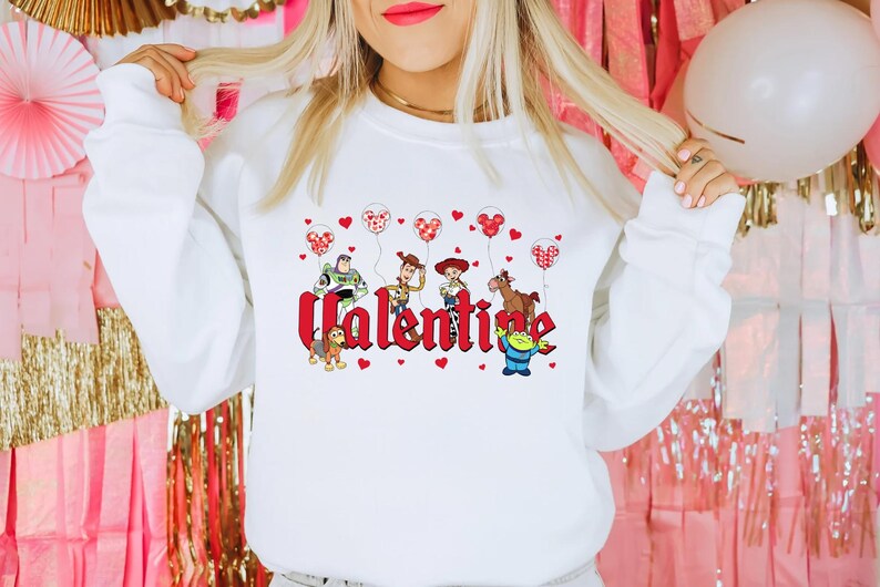 May include: White sweatshirt with a red "Valentine" graphic featuring characters from the Toy Story franchise holding red heart balloons.