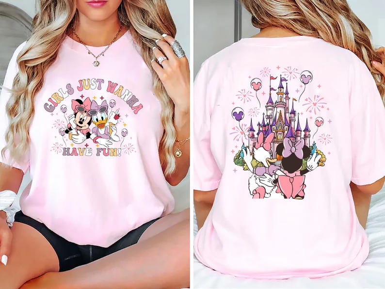 May include: Pink t-shirt featuring Minnie Mouse and Daisy Duck with the text "GIRLS JUST WANNA HAVE FUN!" on the front. The back of the shirt shows a castle and the same characters. The design includes fireworks and balloons.