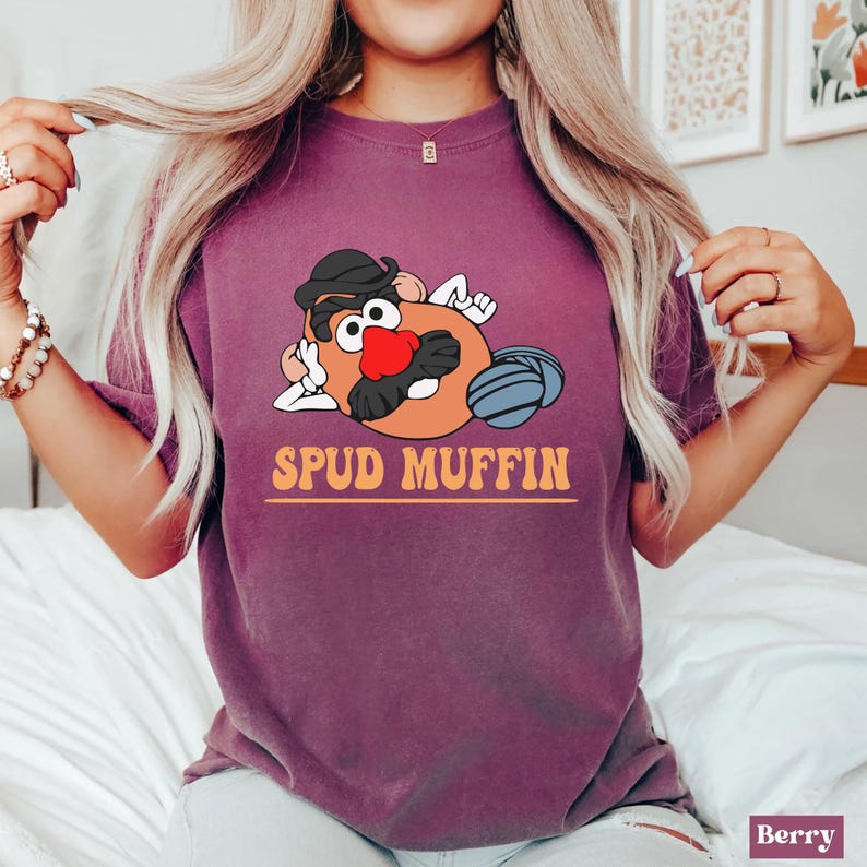 May include: A purple t-shirt with a cartoon image of Mr. Potato Head with the text "Spud Muffin" printed on the front.