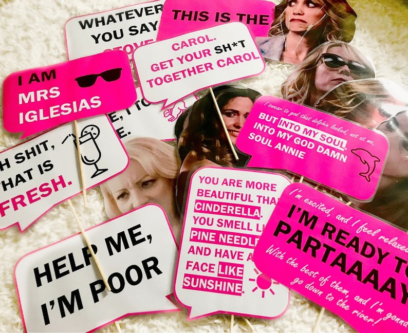 Op de afbeelding: Een set van 10 roze en witte fotobooth-rekwisieten met humoristische uitspraken en afbeeldingen. De rekwisieten bevatten zinnen als "Ik ben mevrouw Iglesias", "Help me, ik ben arm", "Dit is de Carol" en "Ik ben klaar om te feesten".