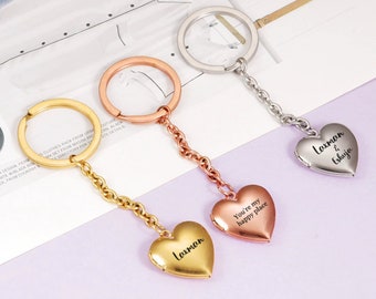 May include: Three heart-shaped locket keychains with different engravings. The gold keychain says "Laxman", the rose gold keychain says "You're my happy place", and the silver keychain says "Laxman & Eshuja".