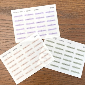 May include: Three sheets of stickers with the word "weekend" written in different styles and colors. The top sheet has lavender colored stripes and the word "weekend" written in a script font. The middle sheet has peach colored stripes and the word "weekend" written in a script font. The bottom sheet has green colored stripes and the word "weekend" written in a script font.