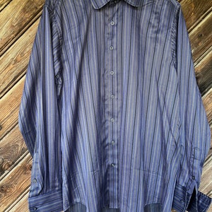 Può includere: Una camicia a maniche lunghe a righe blu e nere. La camicia ha un colletto classico e una chiusura con bottoni.