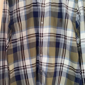 Könnte beinhalten: Ein langärmliges Hemd mit Knöpfen und einem karierten Muster in Grün-, Blau- und Weißtönen. Das Hemd hat einen Knopfkrag und ein kleines Logo auf der Brust, das "Marc O'Polo" lautet.