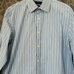 May include: A blue and white striped long-sleeve dress shirt with a button-down collar. The shirt has a label that says "OSBORNE".