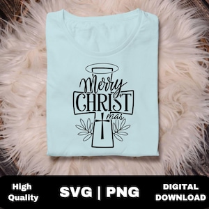 Op de afbeelding: Een lichtblauw T-shirt met een zwarte afbeelding van 'Merry CHRISTmas' in een kruisvorm, met een halo en bladeren. Het shirt is opgevouwen op een zacht, wit oppervlak. De onderkant van de afbeelding toont 'High Quality SVG | PNG DIGITAL DOWNLOAD'.