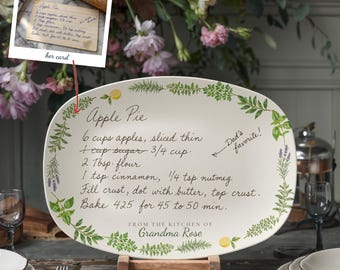 May include: An oval ceramic serving platter featuring a printed Apple Pie recipe in black cursive script. The border is decorated with green herbs and yellow lemons. The text reads: From the kitchen of Grandma Rose, Dad's favorite, and the recipe.