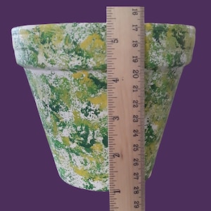 May include: A green and yellow painted terracotta flower pot with a white background. The pot is 6 inches tall.