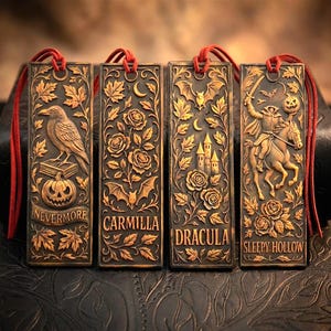 May include: Four bronze-colored rectangular bookmarks with red cords. Each bookmark features a different embossed design: a raven, roses and bats, a castle, and a headless horseman. The bookmarks have the words "Nevermore", "Carmilla", "Dracula", and "Sleepy Hollow".