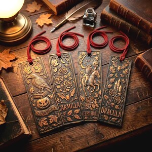 May include: Four antique-style metal bookmarks with red cords, featuring embossed designs and text. The designs include a raven, roses, a headless horseman, and a castle. The text on the bookmarks reads "Nevermore", "Carmilla", "Sleepy Holl", and "Dracula".