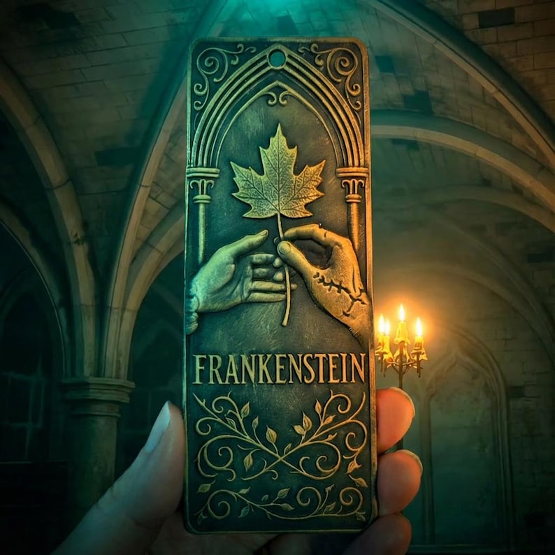 May include: A rectangular, bronze-colored plaque with the word "FRANKENSTEIN" in white lettering. The plaque features a relief of two hands holding a maple leaf. The background is a gothic-style interior with arched ceilings and candlelight.