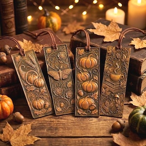 Pode incluir: Quatro marcadores de metal cor de bronze com cordões de couro castanho. Cada marcador apresenta um design em relevo diferente: abóboras, uma traça, uma cornucópia e uma chávena de café. Decorações com tema de outono.