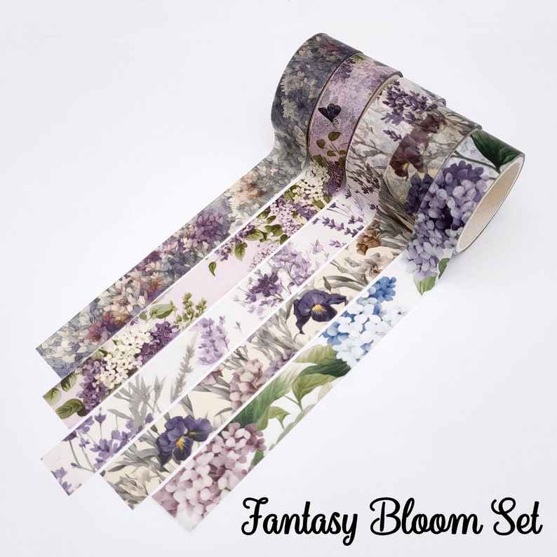 May include: A set of four rolls of decorative adhesive tape featuring floral patterns in shades of purple, blue, and green. The designs include illustrations of hydrangeas, lavender, and other blossoms. The text Fantasy Bloom Set is printed below.